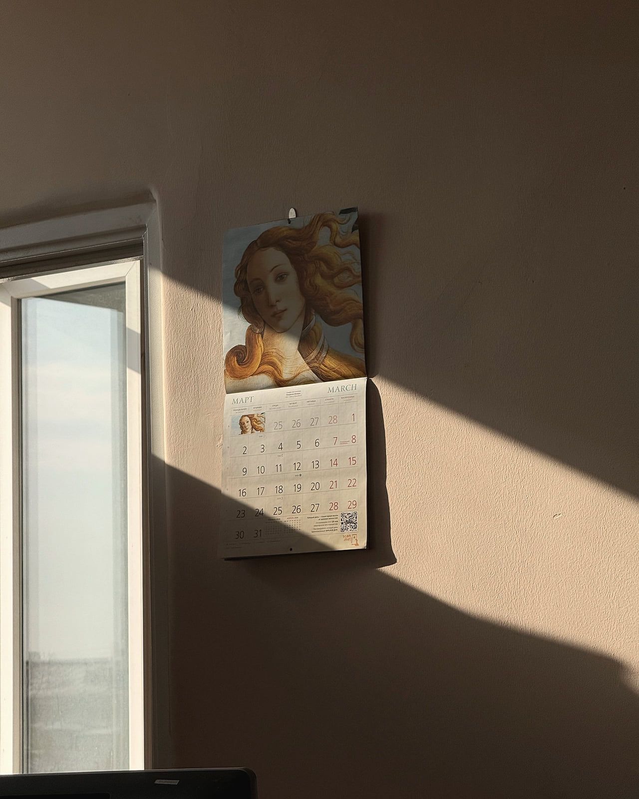 Un calendrier mural éclairé par le soleil du matin, dans une entrée.