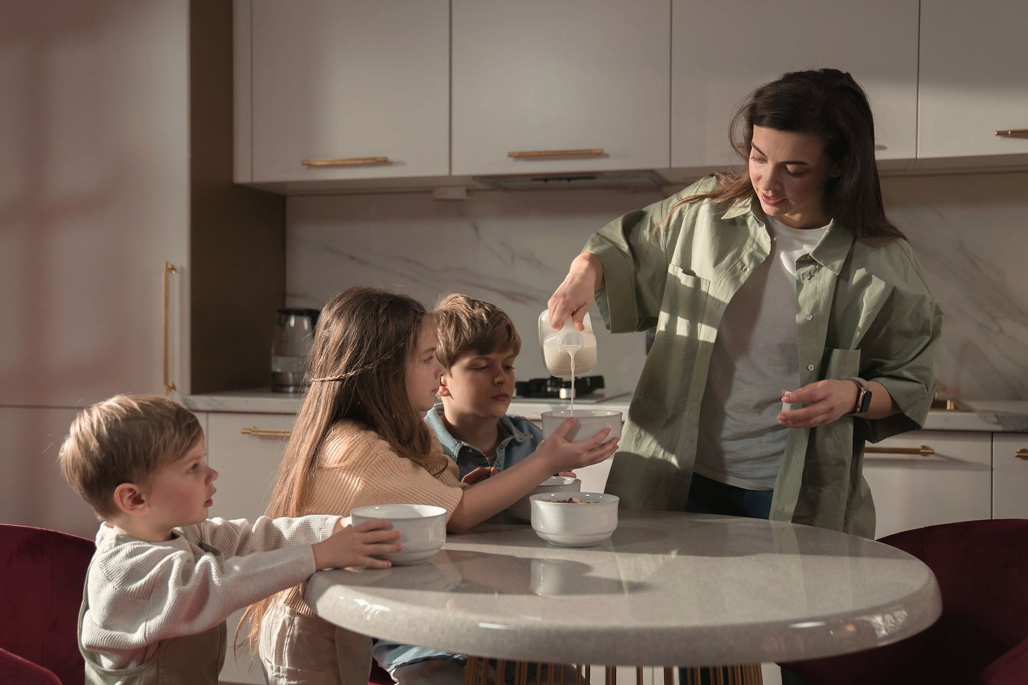 Une mère sert le petit-déjeuner à ses trois enfants.