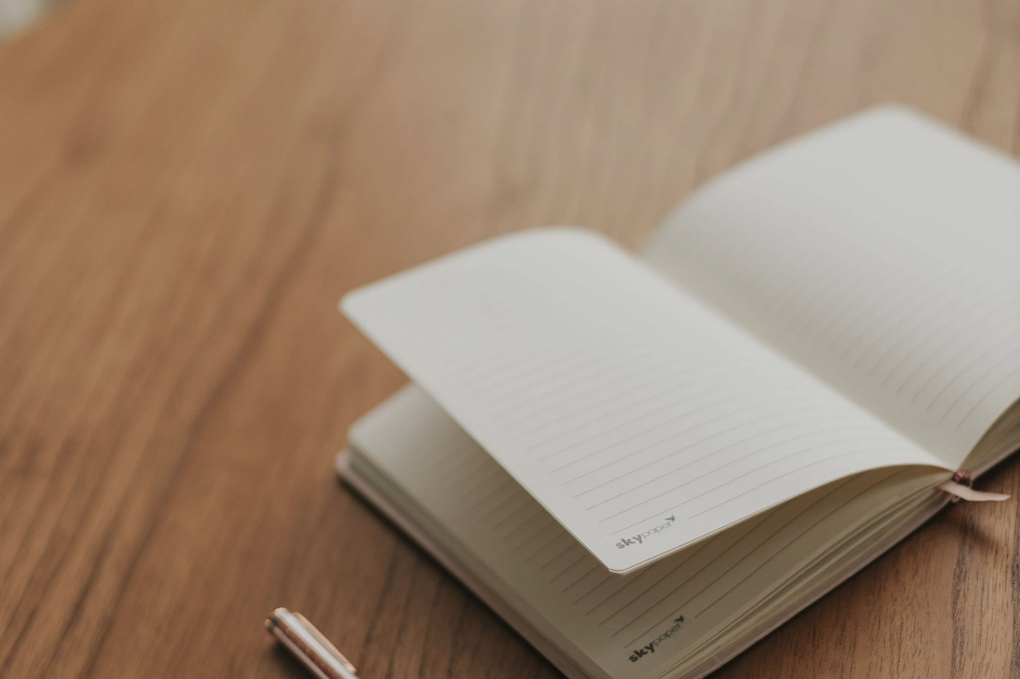 Un carnet ouvert et un stylo sur une table en bois.