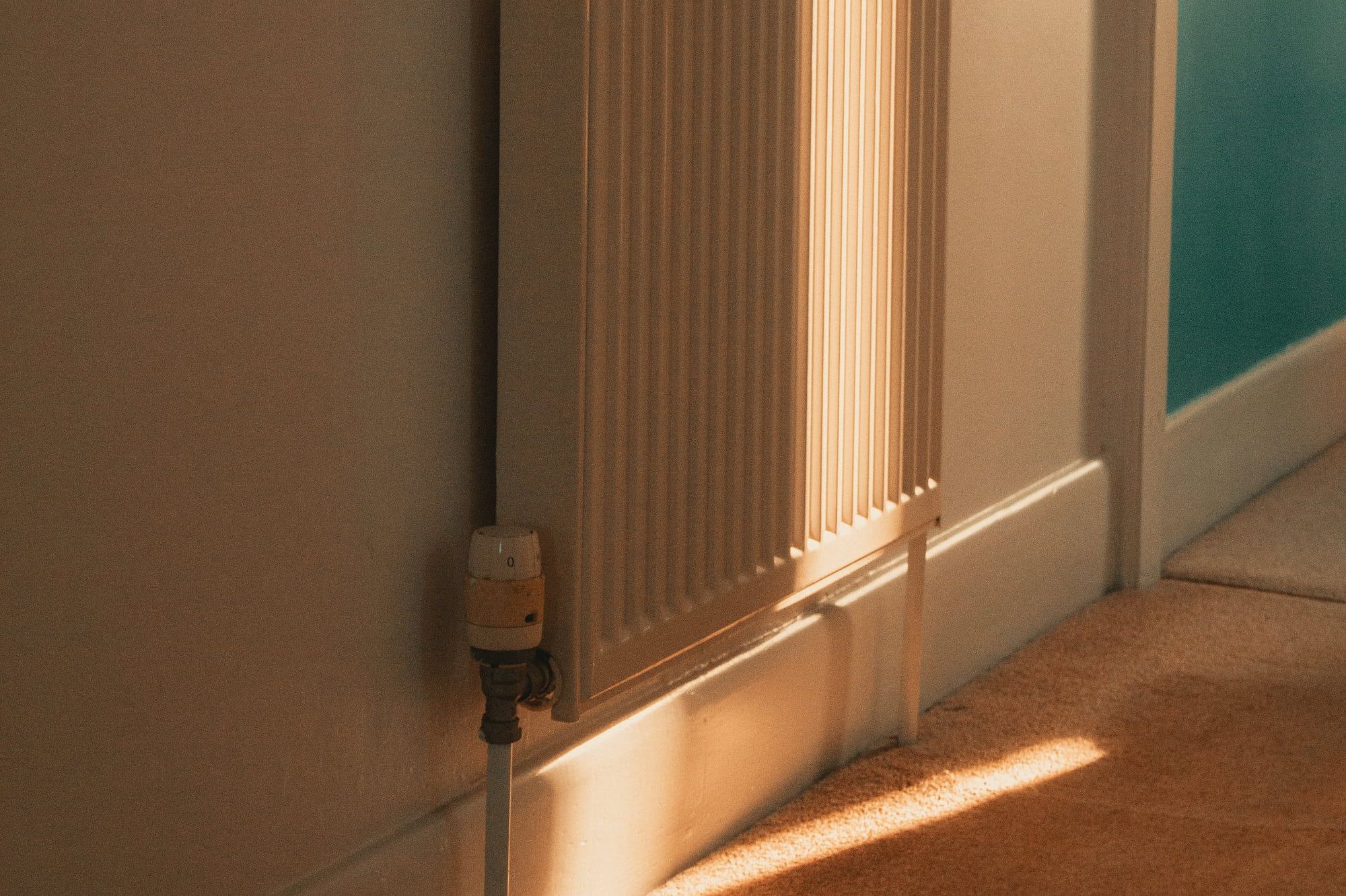 Un radiateur dans un couloir, éclairé par la lumière du soir.