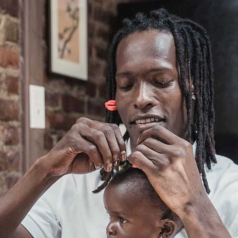Un père coiffe sa petite fille.